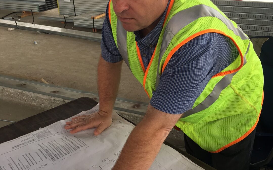 Construction worker reviewing blueprints at a site.